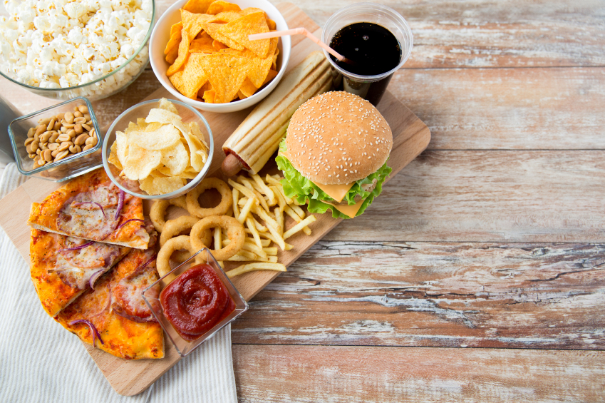 fast food and unhealthy eating concept - close up of fast food snacks and coca cola drink on wooden table