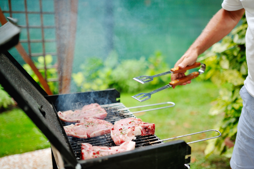 Man at barbecue grill preparing meat for a garden party